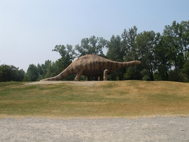 A model of a brontosaurus in front of some trees.